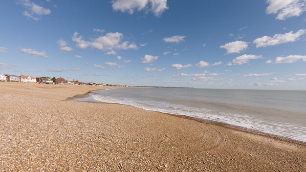 Strand umgeben vom Meer und Gebäuden unter dem Sonnenlicht und einem blauen Himmel am Tag