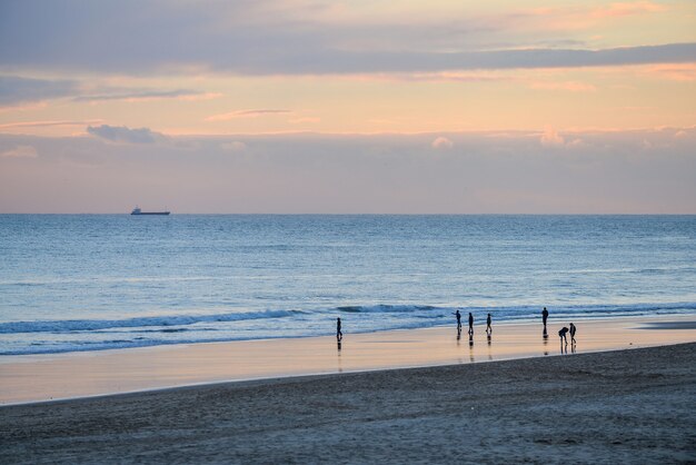 Strand umgeben vom Meer und Menschen unter einem bewölkten Himmel während eines schönen Sonnenuntergangs