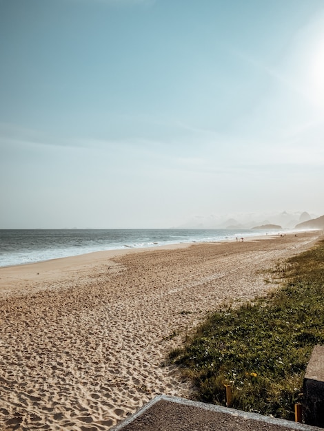 Strand, umgeben von Meer und Gras im Sonnenlicht in Rio de Janeiro, Brasilien