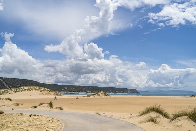 Strand, umgeben von Meer und Hügeln im Grünen unter einem bewölkten Himmel in Andalusien, Spanien