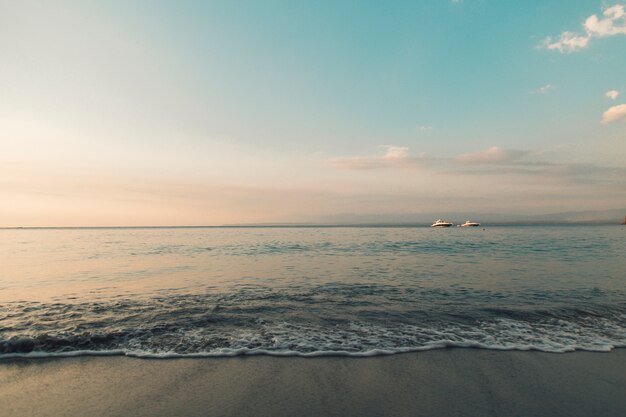 Strand und ruhiger Ozean in den Sonnenunterganglichtern