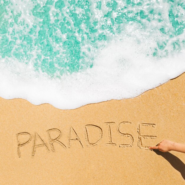 Strandkonzept mit dem Paradies geschrieben in Sand