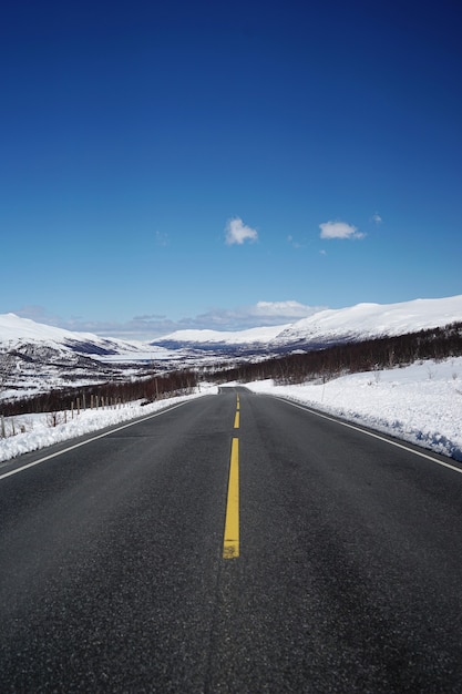 Straße führt zu schönen schneebedeckten Bergen