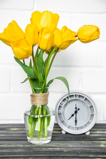 Kostenloses Foto strauß gelber tulpen und einer retro-uhr