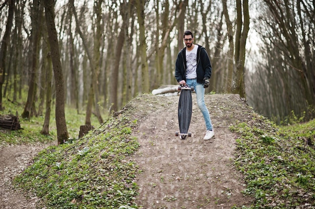 Street Style arabischer Mann in Brille mit Longboard auf Holz