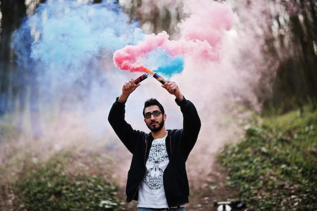 Street Style arabischer Mann mit Brille hält Handfackel mit roter und blauer Rauchgranatenbombe