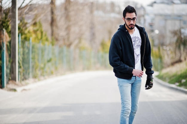 Street Style arabischer Mann mit Brille mit Longboard Longboarding die Straße hinunter