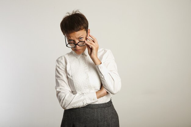 Strenge Lehrerin sieht missbilligend aus und passt ihre Brille an