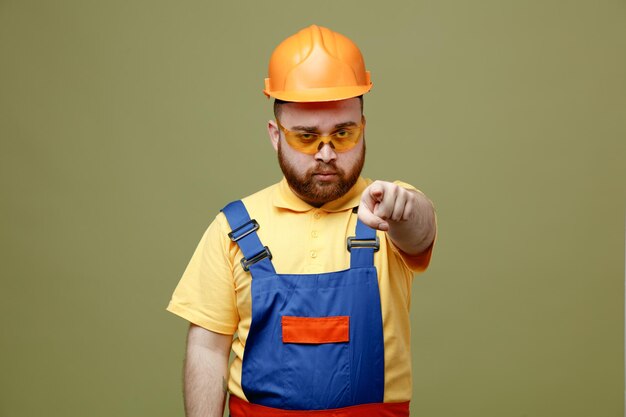 Kostenloses Foto strenge punkte auf kamera junger baumeister mann in uniform isoliert auf grünem hintergrund