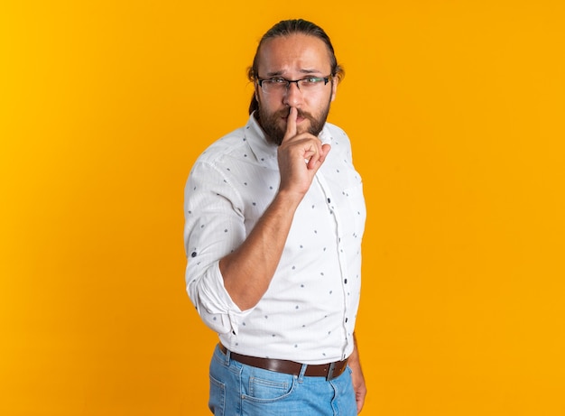 Strenger erwachsener gutaussehender Mann mit Brille, der in der Profilansicht steht und Stillegeste macht