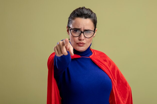 Strenges junges Superheldenmädchen, das Brillen trägt, die Sie Geste lokalisiert auf olivgrünem Hintergrund zeigen