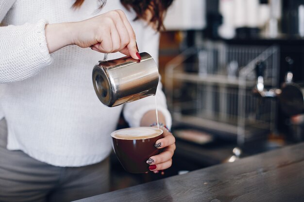 Strömender Milchschaum obenliegender Ansicht weibliches barista in Cappuchino im Café