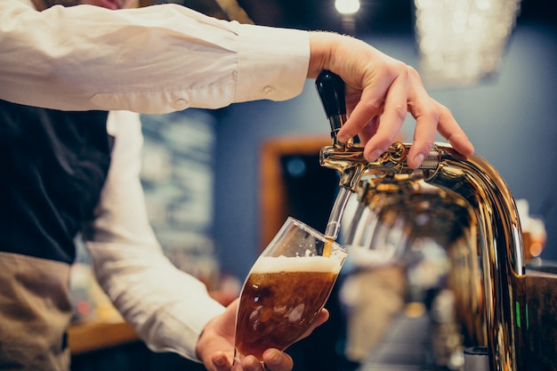 Kostenloses Foto strömendes bier des männlichen barmixers an einer kneipe