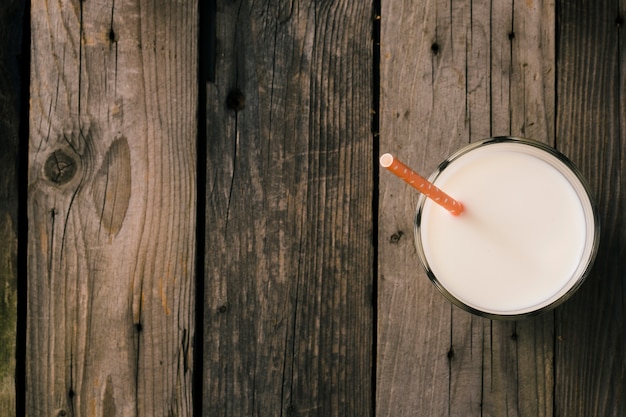 Stroh im Glas Milch über dem rustikalen hölzernen Hintergrund