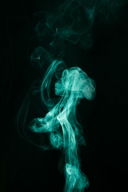 Strudel des grünen Rauches verschiebt sich auf schwarzen Hintergrund