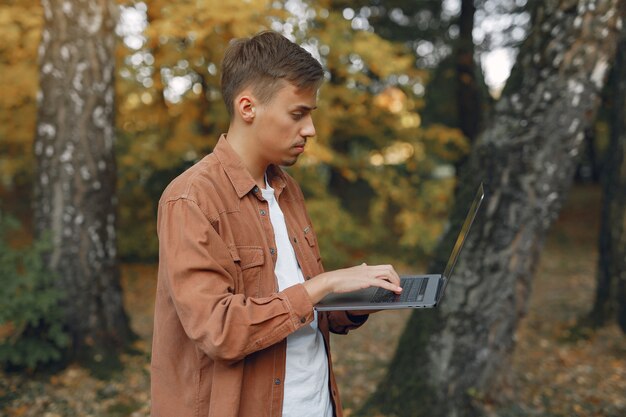 Student arbeitet in einem Park und benutzt den Laptop