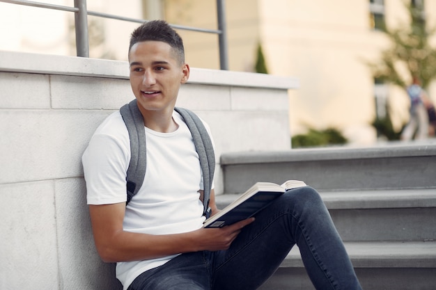 Student auf einem Universitätscampus mit einem Buch