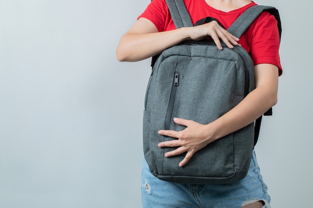 Student hält den grauen Rucksack vorne