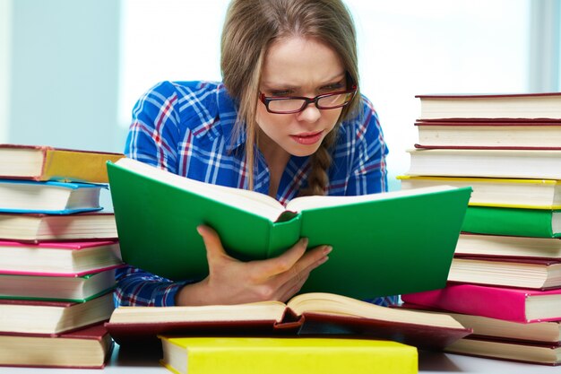 Student mit Brille liest auf einmal mehrere Bücher