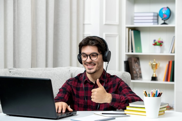 Student online süßer Typ in kariertem Hemd mit Brille, der am Computer studiert und eine gute Geste zeigt