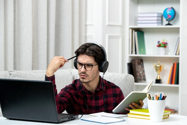 Student online süßer Typ in kariertem Hemd mit Brille, der konzentriert am Computer studiert