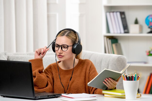 Student online süßes Mädchen in Brille und Pullover, das am Computer studiert und Vorlesungen hört