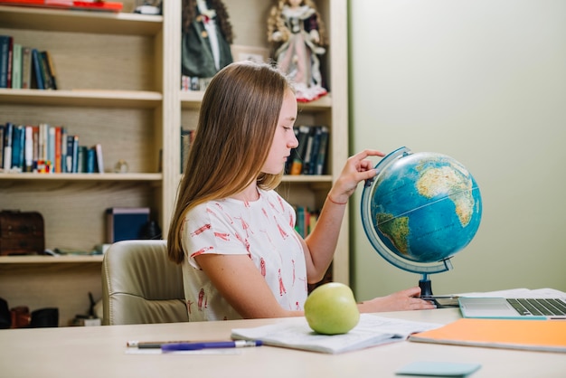Student posiert mit Globus am Tisch
