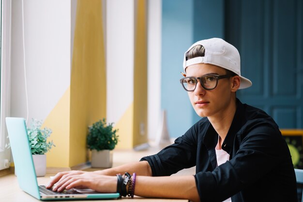Student posiert mit Laptop im Klassenzimmer