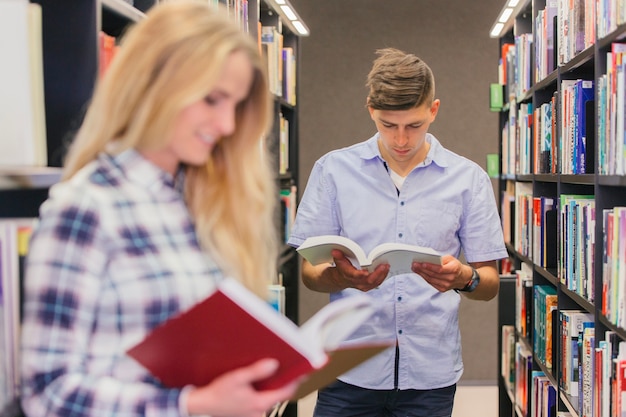 Studenten, die Bücher zwischen Bücherregalen lesen