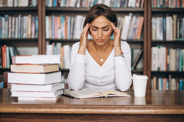 Kostenloses Foto studentenfrau, die an der bibliothek studiert und kaffee trinkt