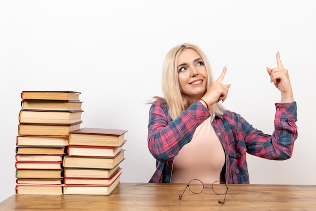 Kostenloses Foto studentin, die gerade mit büchern auf weiß sitzt