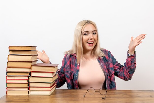 Studentin, die gerade mit Büchern auf Weiß sitzt