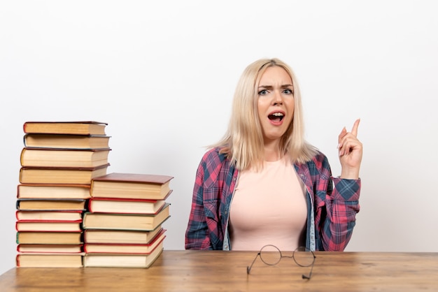 Kostenloses Foto studentin, die gerade mit büchern auf weiß sitzt