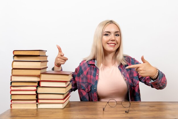 Studentin, die gerade mit Büchern sitzt, die auf Weiß lächeln