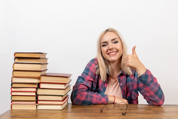 Studentin, die gerade mit verschiedenen Büchern auf Weiß sitzt