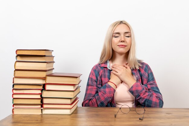 Studentin, die gerade mit verschiedenen Büchern auf Weiß sitzt