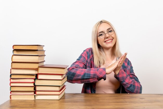 Studentin, die gerade mit verschiedenen Büchern sitzt, die auf Weiß lächeln