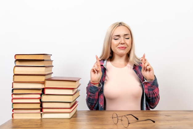 Kostenloses Foto studentin, die mit büchern sitzt und auf weiß aufwirft