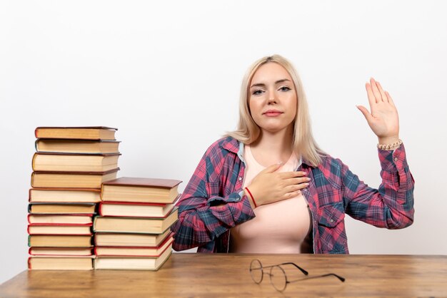 Studentin, die mit Büchern sitzt und auf Weiß aufwirft