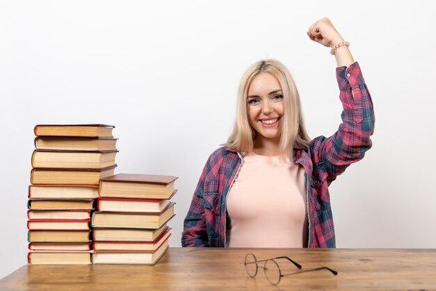 Studentin, die mit Büchern sitzt und auf Weiß aufwirft