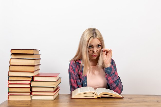 Studentin, die mit Büchern sitzt und auf Weiß liest