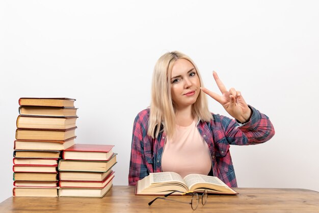 Studentin, die mit Büchern sitzt und auf Weiß liest