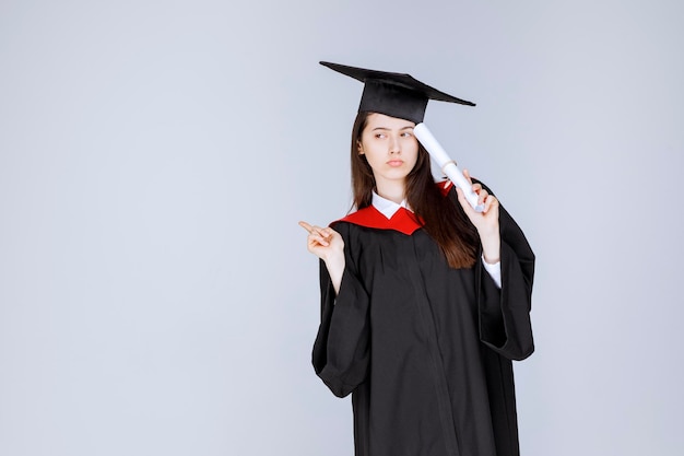 Studentin im Aufbaustudium im Kleid mit Hochschulzertifikat. Foto in hoher Qualität