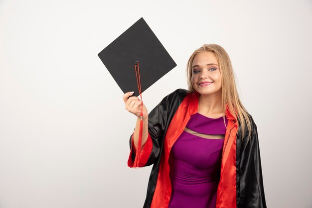 Studentin im Kleid, das auf weißer Wand steht.