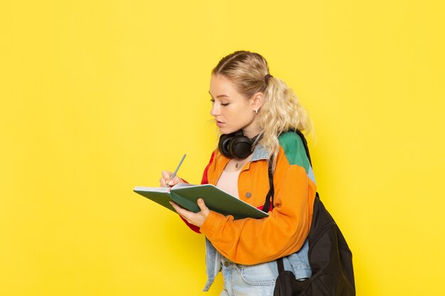 Studentin jung in modernen Kleidern, die Notizen auf Gelb aufschreiben