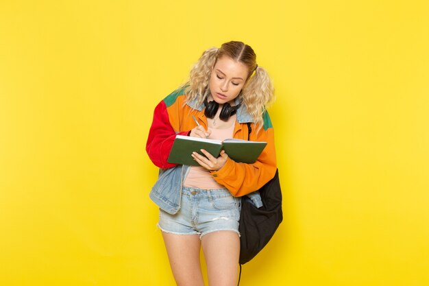 Studentin jung in modernen Kleidern, die Notizen auf Gelb aufschreiben