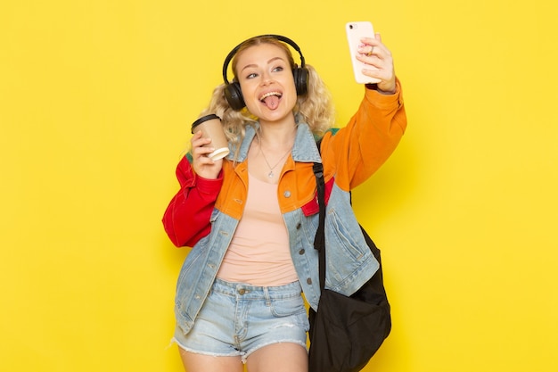 Studentin jung in moderner Kleidung, die ein Selfie auf Gelb nimmt