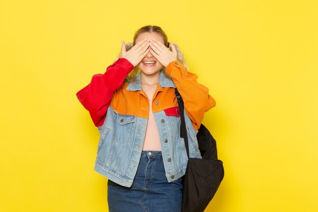 Studentin jung in moderner Kleidung, die ihre Augen auf Gelb bedeckt