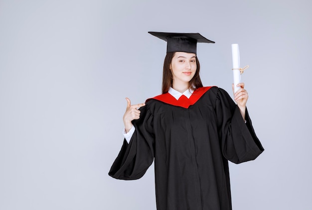 Studentin mit College-Diplom posiert vor der Kamera. Foto in hoher Qualität