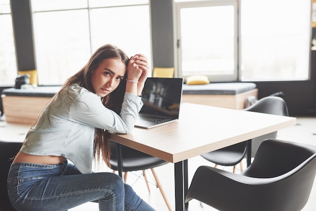 Studentin mit Laptop beim Sitzen im Café. Konzentrierte junge Frau freiberuflich bei der Arbeit.